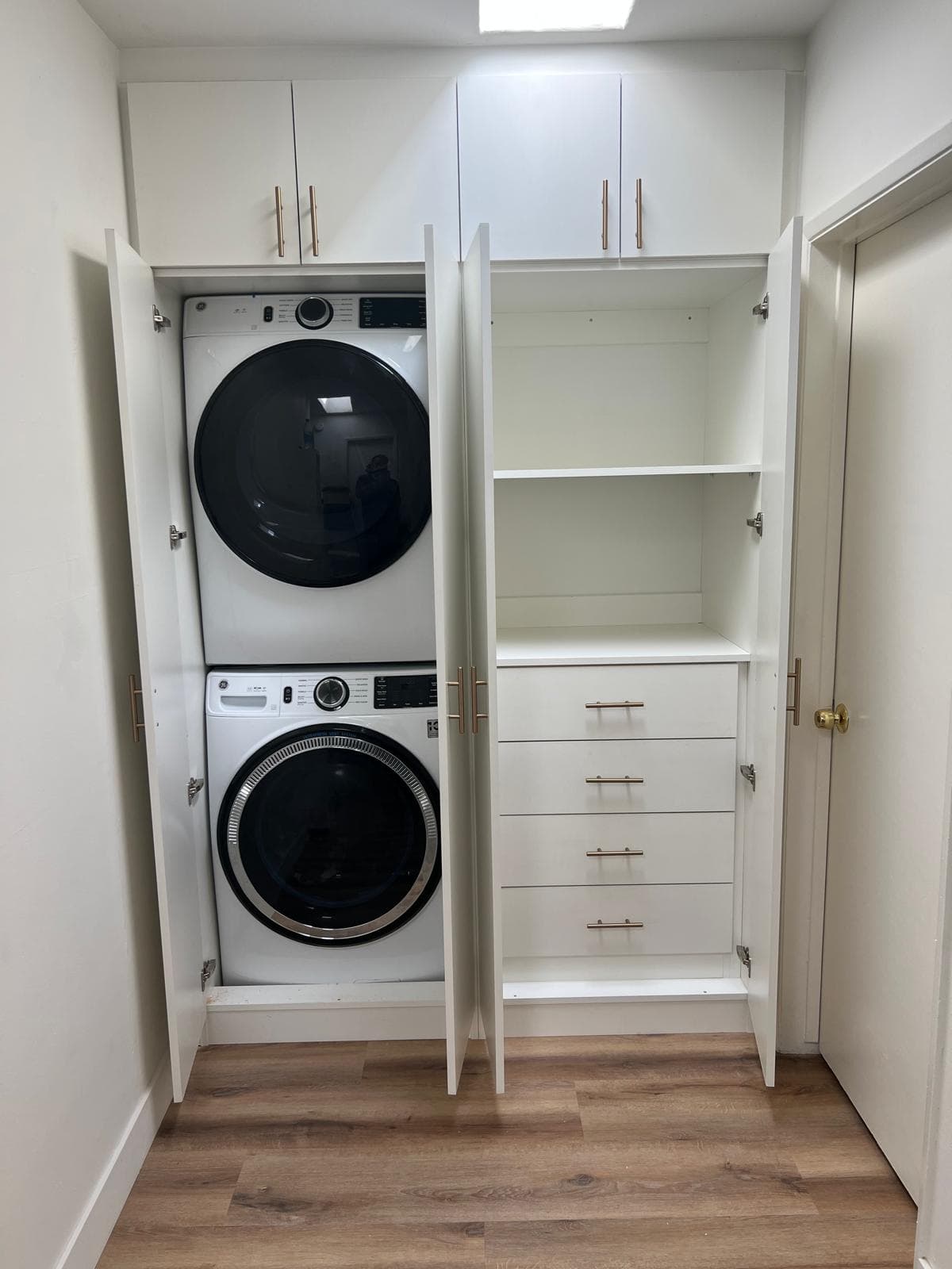 Custom built-in laundry cabinets in white with brass handles