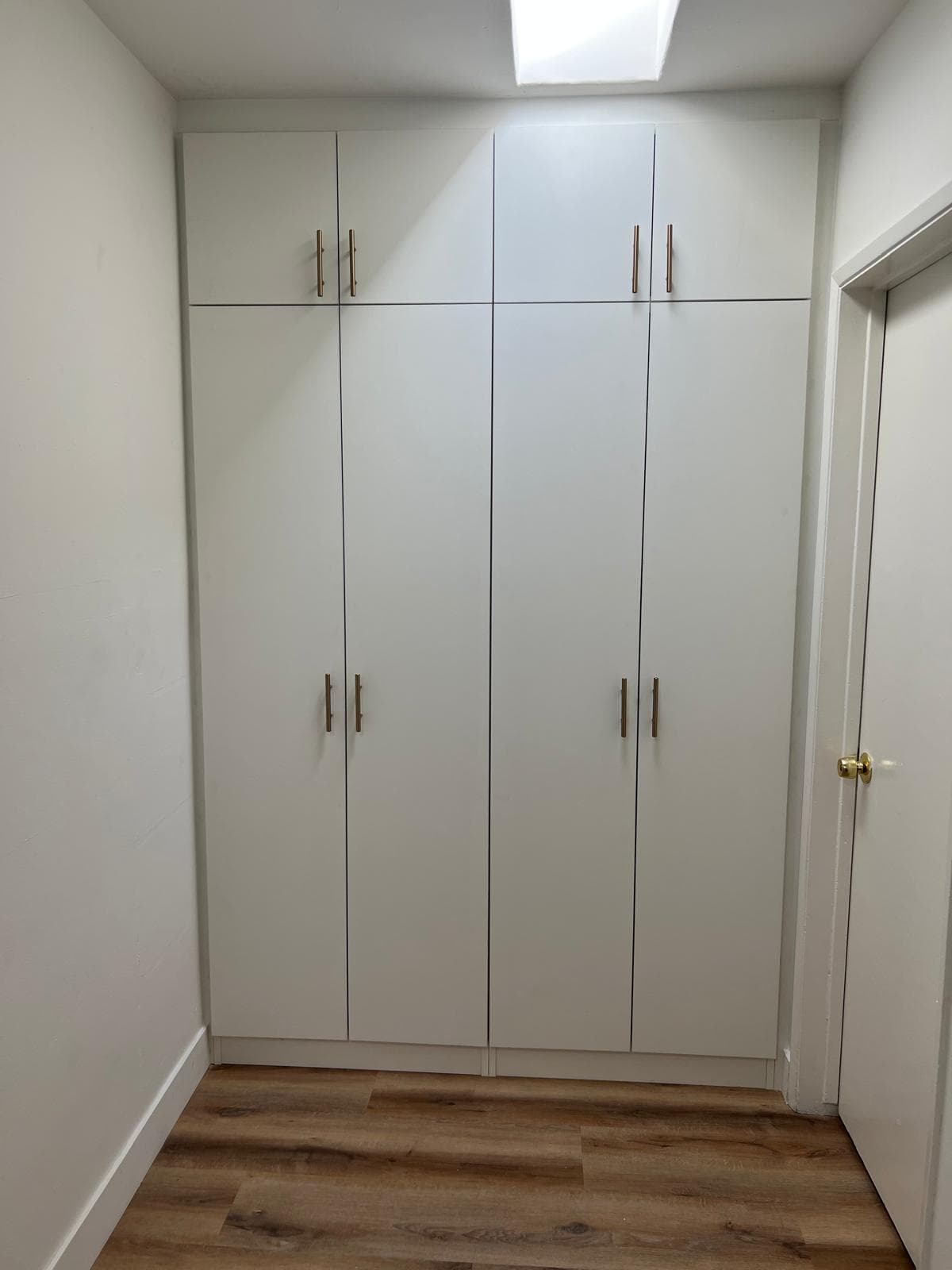Detail of brass handles on white built-in laundry cabinets