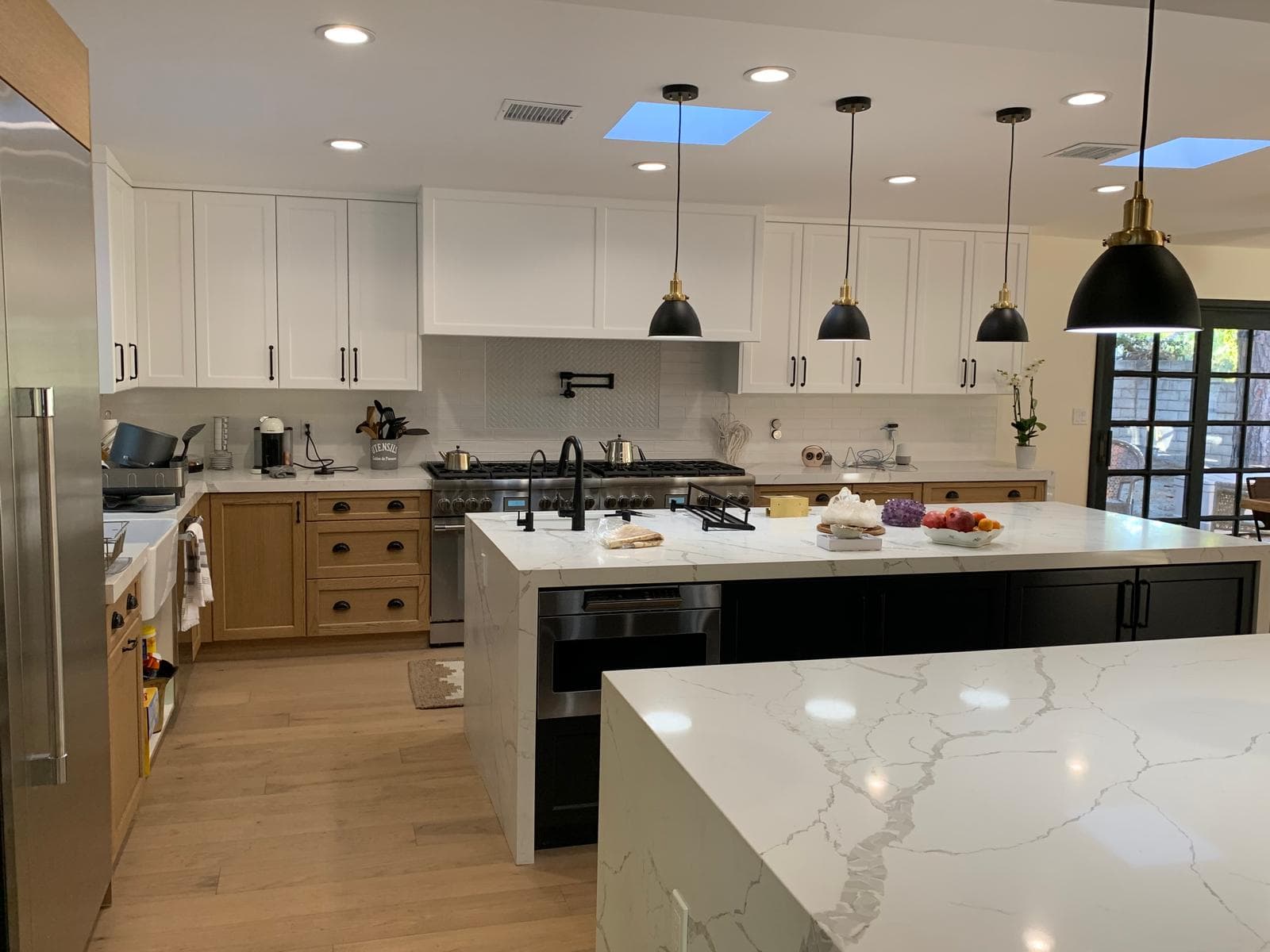 Transitional kitchen with white wood cabinets and marble countertops